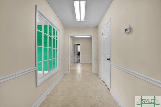 hallway featuring light tile patterned floors and baseboards