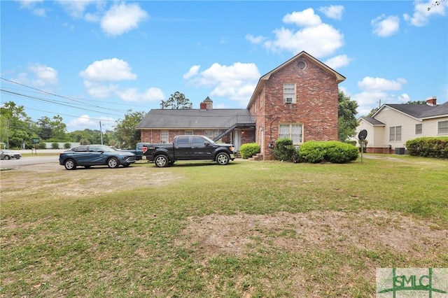 exterior space with brick siding, a front lawn, and central air condition unit