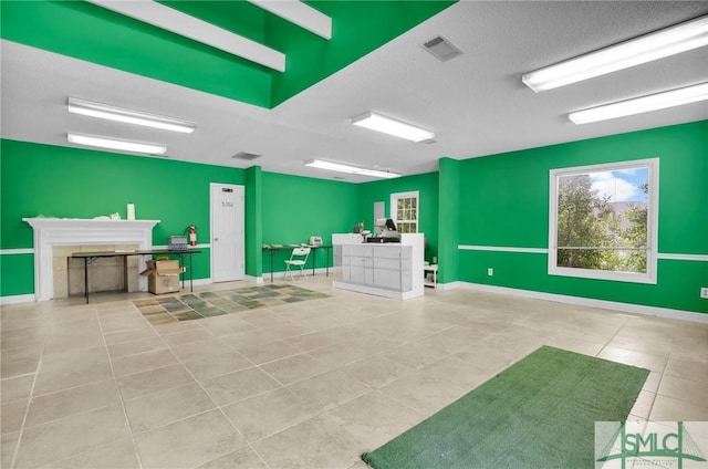 exercise room featuring tile patterned floors, visible vents, a textured ceiling, and a fireplace