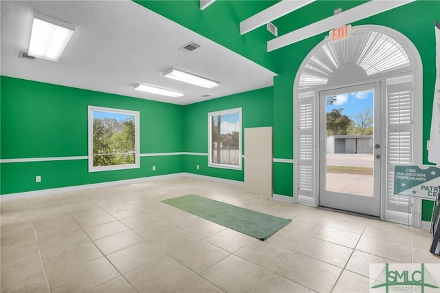 interior space featuring baseboards, visible vents, and a healthy amount of sunlight
