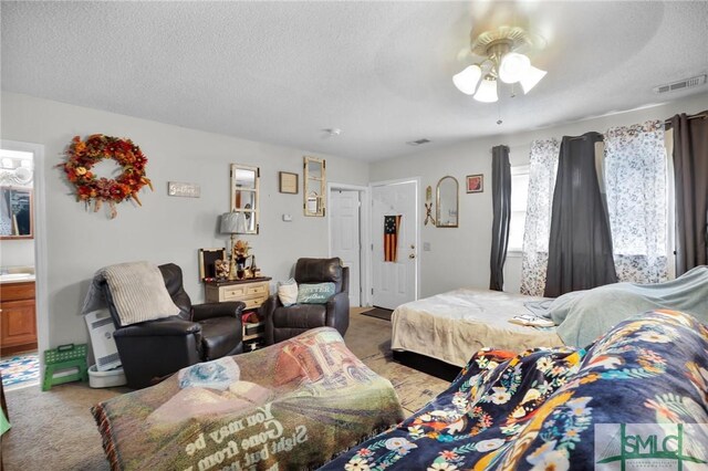 bedroom with light colored carpet, visible vents, and a textured ceiling