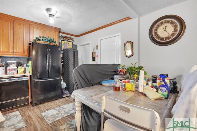 kitchen featuring light wood-style floors, light countertops, black appliances, ornamental molding, and a textured ceiling