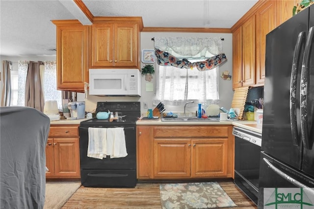 kitchen featuring black appliances, a wealth of natural light, light countertops, and a sink
