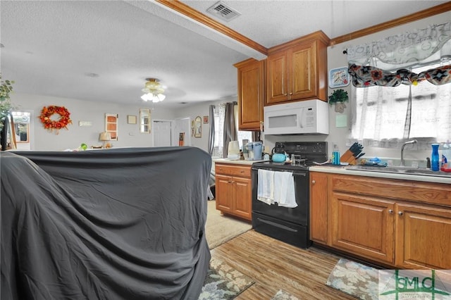 kitchen featuring white microwave, brown cabinetry, a sink, black range with electric stovetop, and visible vents