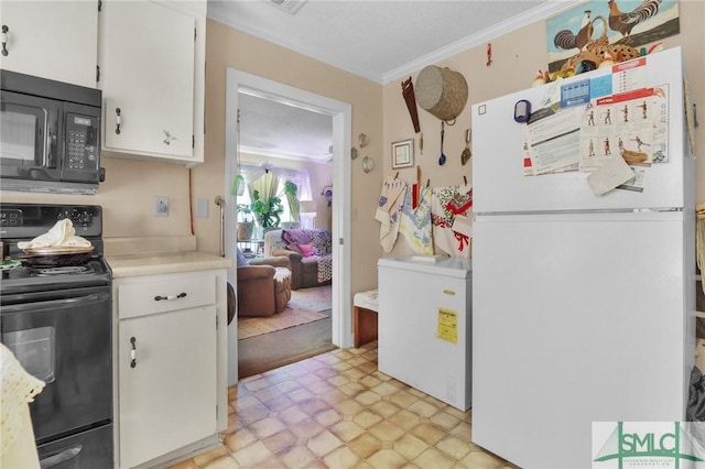 kitchen with crown molding, range, black microwave, light countertops, and freestanding refrigerator