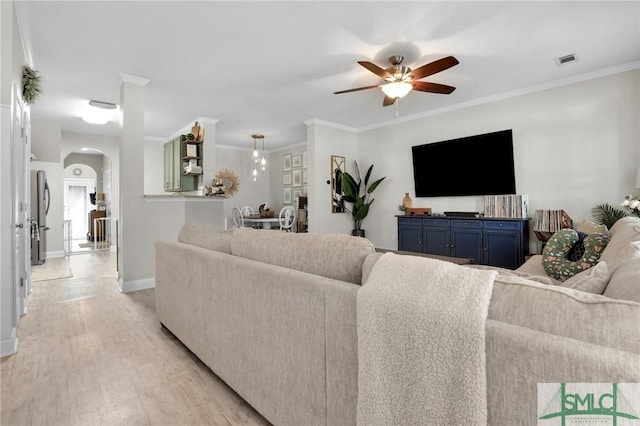 living area featuring visible vents, baseboards, arched walkways, light wood finished floors, and a ceiling fan