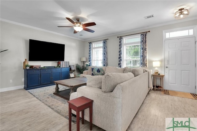 living area with light wood-style flooring, baseboards, visible vents, a ceiling fan, and crown molding