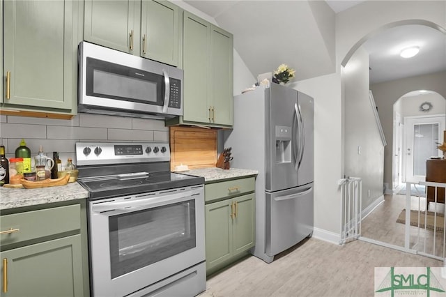 kitchen featuring arched walkways, green cabinets, and stainless steel appliances