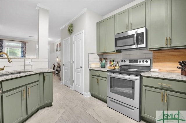 kitchen with appliances with stainless steel finishes, green cabinetry, decorative backsplash, and a sink
