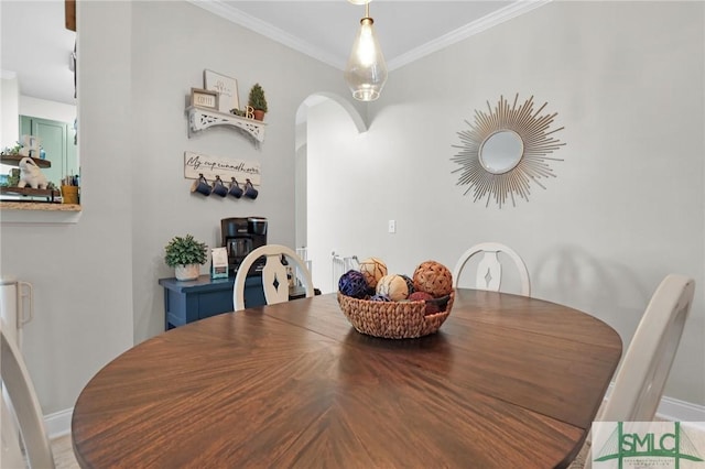 dining space with ornamental molding, arched walkways, and baseboards