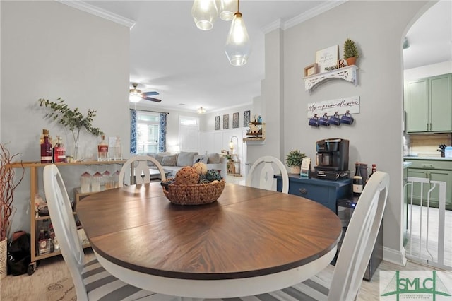 dining space with arched walkways, ceiling fan, and crown molding