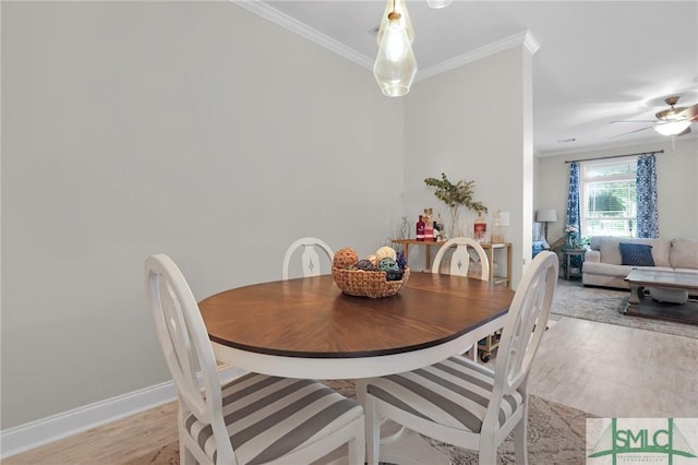 dining area with baseboards, ornamental molding, ceiling fan, and light wood-style floors