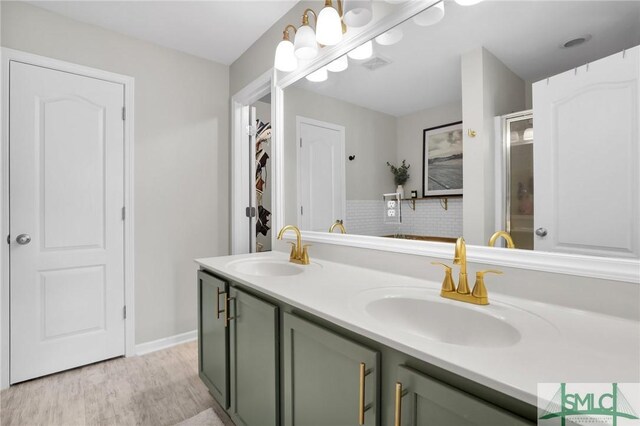 full bath featuring double vanity, wood finished floors, visible vents, and a sink