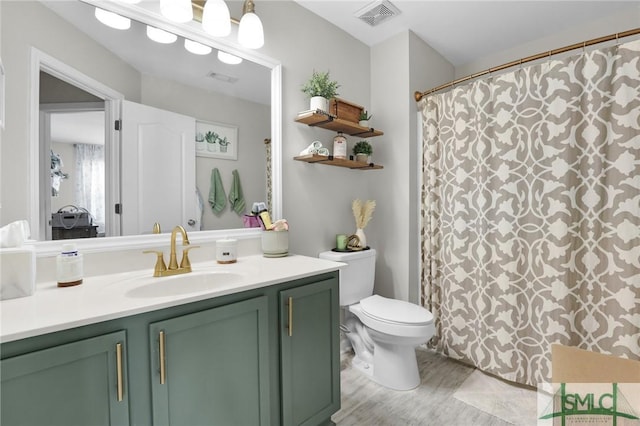 full bath featuring toilet, wood finished floors, visible vents, and vanity