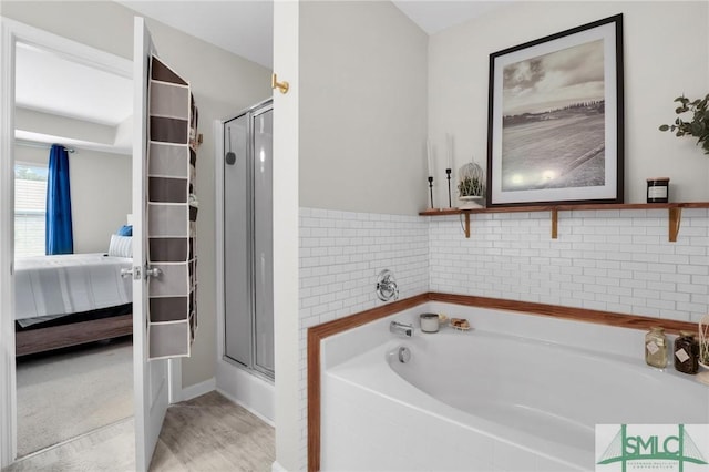 bathroom with a garden tub, a stall shower, wood finished floors, and ensuite bathroom