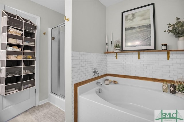 full bathroom featuring a garden tub, a stall shower, and wood finished floors