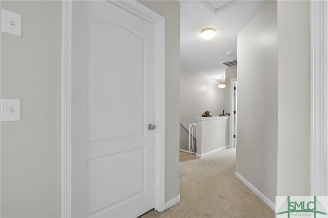 hall featuring baseboards, visible vents, light carpet, and an upstairs landing