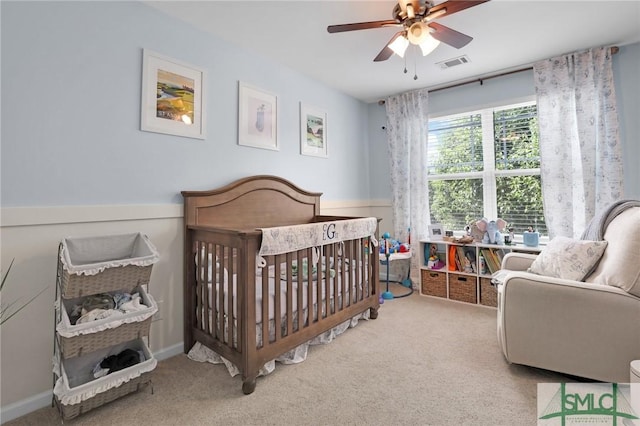 bedroom with visible vents, ceiling fan, carpet flooring, and a crib