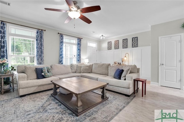 living area featuring visible vents, a ceiling fan, light wood finished floors, and crown molding