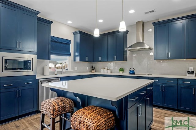 21 Shoefstall St, Savannah, GA 31407 - kitchen with wall chimney range hood, stainless steel appliances, and blue cabinets