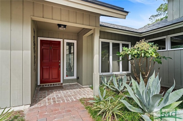 view of exterior entry featuring roof with shingles
