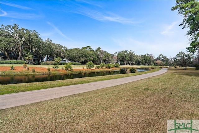 view of home's community with concrete driveway, a water view, and a yard
