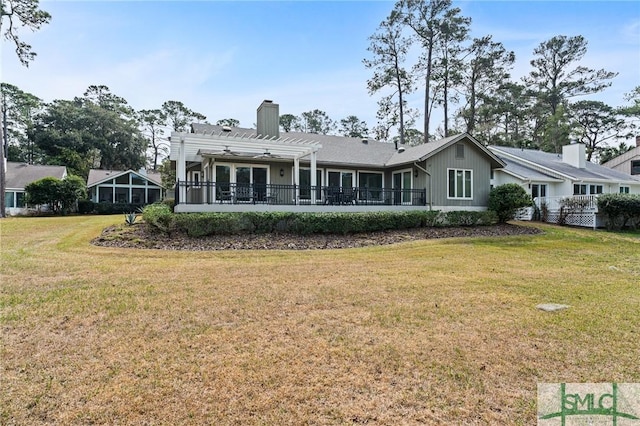 rear view of house with a lawn, board and batten siding, a pergola, and a chimney