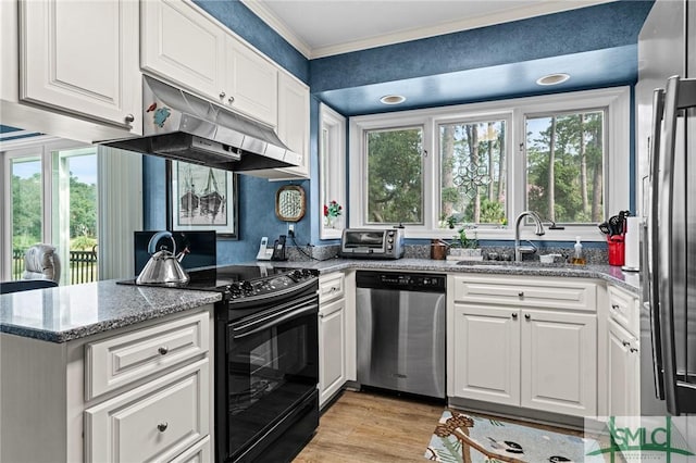 kitchen featuring crown molding, under cabinet range hood, white cabinets, a sink, and stainless steel appliances