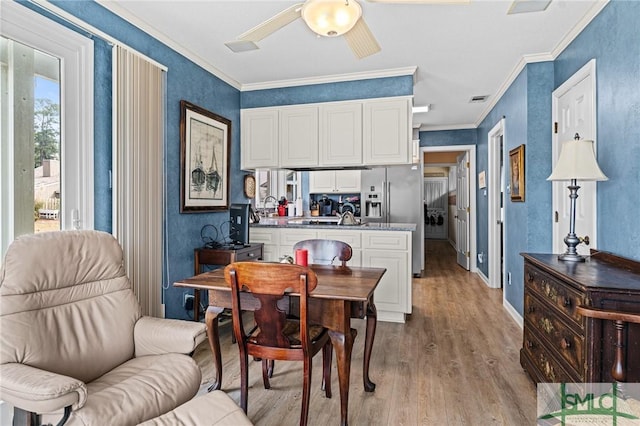 dining space with crown molding, a ceiling fan, baseboards, wood finished floors, and visible vents