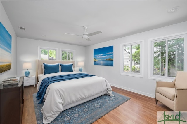 bedroom with visible vents, a ceiling fan, baseboards, and wood finished floors