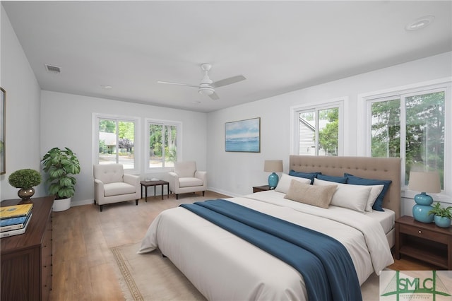 bedroom with visible vents, baseboards, multiple windows, and light wood-type flooring