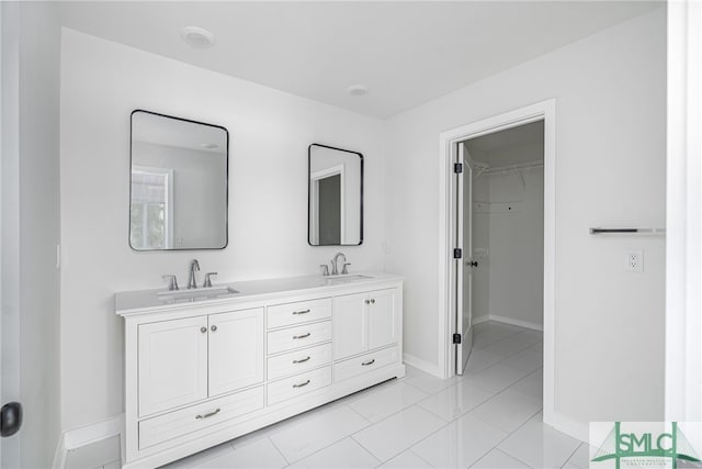full bathroom with baseboards, a sink, double vanity, and a spacious closet