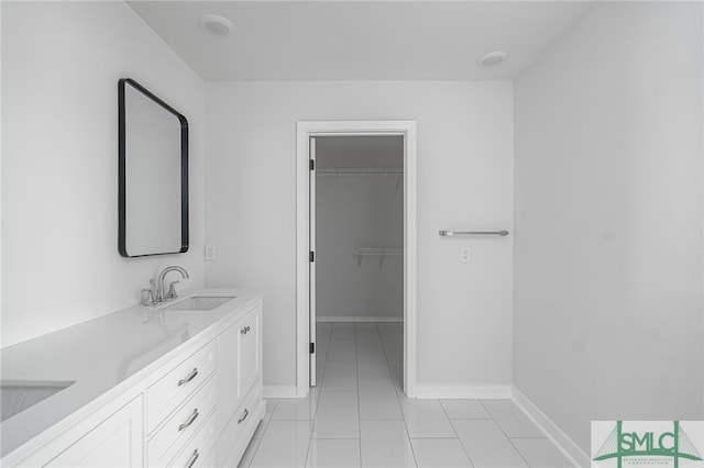 bathroom with double vanity, baseboards, a sink, and tile patterned flooring