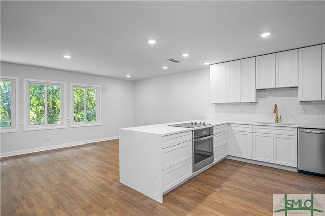 kitchen featuring white cabinets, a sink, stainless steel appliances, a peninsula, and visible vents