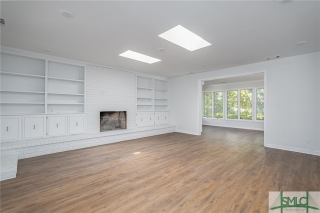 unfurnished living room with visible vents, built in features, a fireplace, baseboards, and a skylight