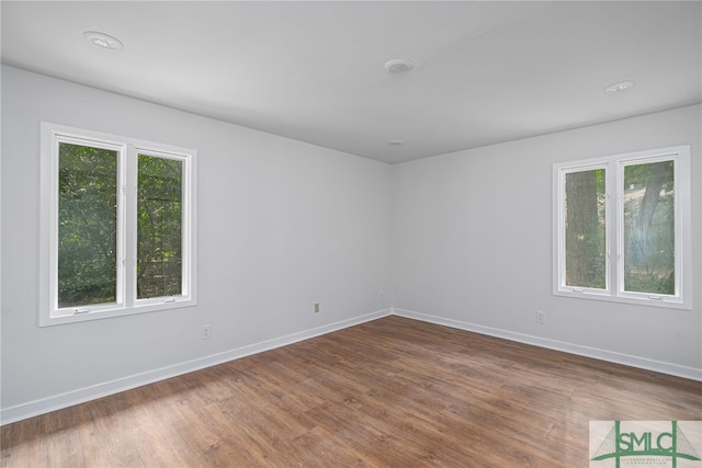 unfurnished room with baseboards, a healthy amount of sunlight, and wood finished floors