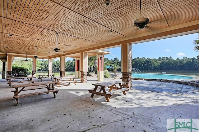 view of patio with a community pool, fence, and ceiling fan