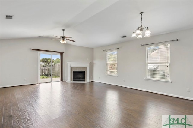 unfurnished living room with a healthy amount of sunlight, ceiling fan with notable chandelier, wood finished floors, and visible vents