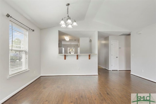 empty room with baseboards, a notable chandelier, lofted ceiling, and dark wood-type flooring