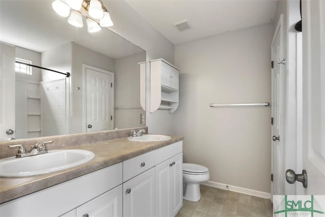 bathroom featuring a sink, baseboards, toilet, and visible vents