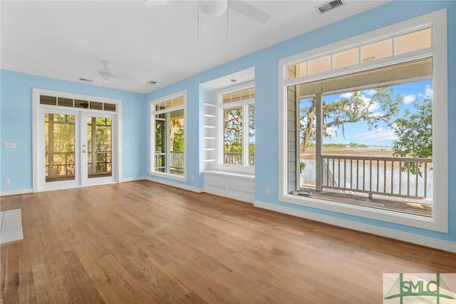 unfurnished sunroom featuring a water view, visible vents, and french doors