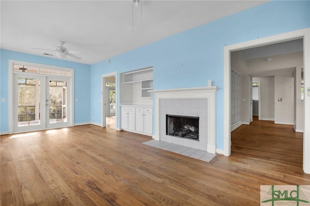 unfurnished living room featuring baseboards, ceiling fan, wood finished floors, and a fireplace