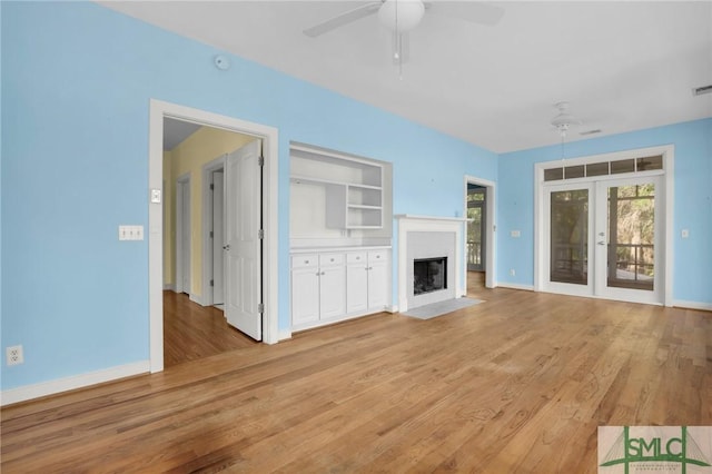 unfurnished living room featuring a fireplace with flush hearth, baseboards, ceiling fan, and light wood-type flooring