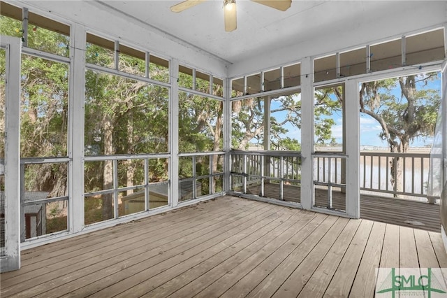 unfurnished sunroom with plenty of natural light, a water view, and ceiling fan