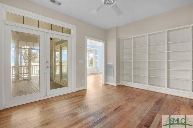 interior space featuring baseboards, a ceiling fan, wood finished floors, and visible vents
