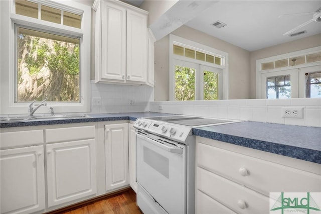 kitchen with visible vents, dark countertops, white electric range, a sink, and white cabinets
