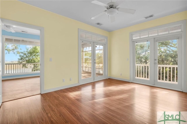 interior space with a ceiling fan, french doors, wood finished floors, and visible vents