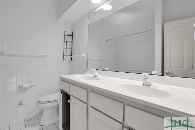 full bath featuring a sink, tile patterned floors, toilet, and double vanity