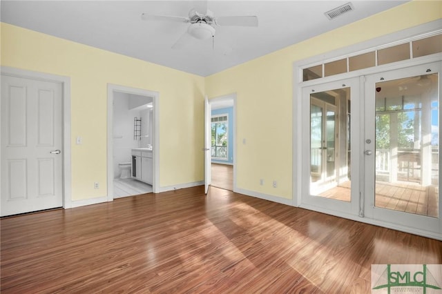 interior space with ceiling fan, french doors, visible vents, wood finished floors, and baseboards