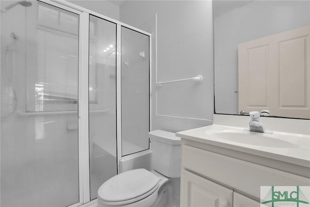 bathroom featuring vanity, a shower with shower door, and toilet